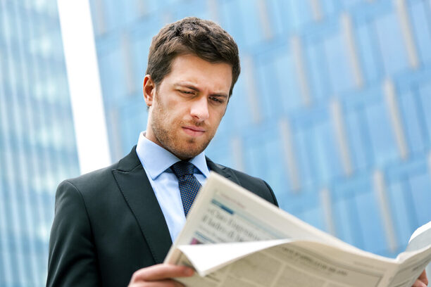 Young businessman reading a newspaper